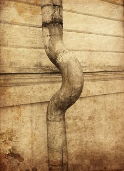 Textured rusty rain pipe against wooden facade pointing right.
