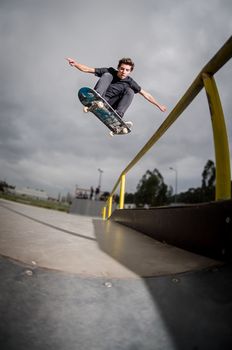 Skateboarder doing a ollie over the rail at the skate park.