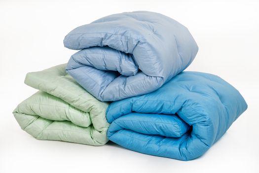 Three coloured down blankets on an isolated studio background