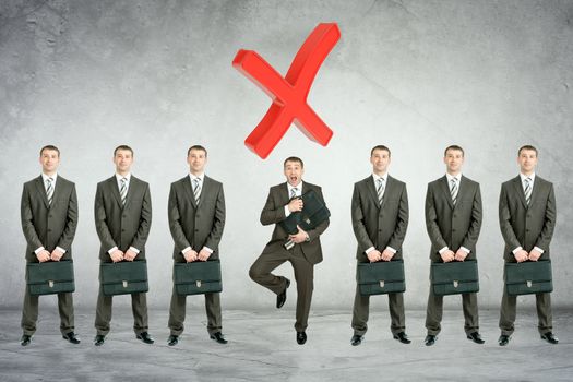 Set of businessmen with big cross on grey wall background