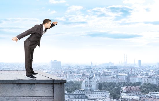 Businessman looking forward on building roof and cityscape background