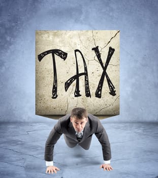 Businessman doing push-ups with stone on back and word tax