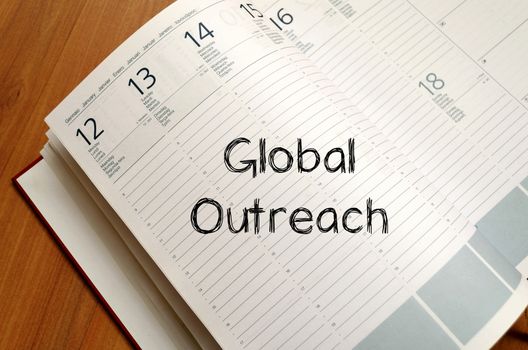 Global outreach text concept write on notebook with pen
