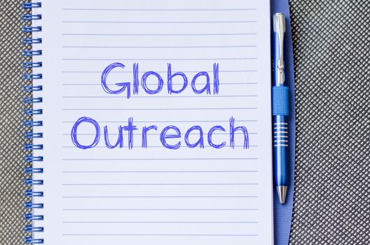 Global outreach text concept write on notebook with pen