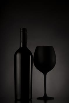Black wine bottle and black glass of wine on black background