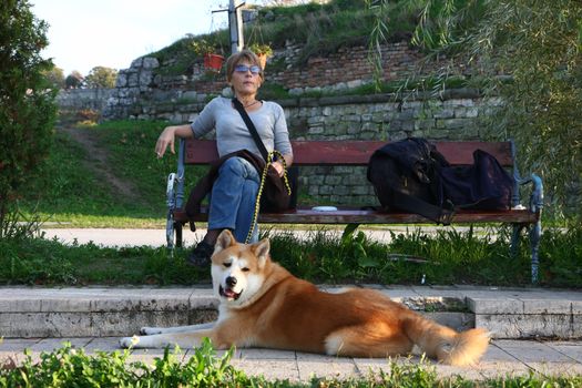 Lady with Akita inu enjoying on the bench in the city park
