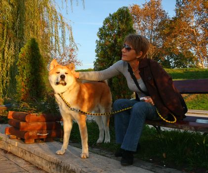 Lady with Akita inu enjoying on the bench in the city park