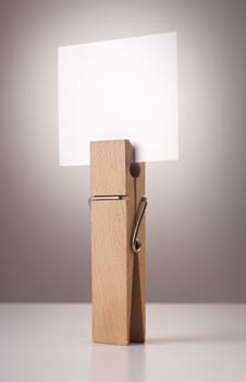 wooden peg holding a white note isolated on grey background