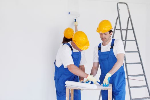 Team of builders with construction plan indoors