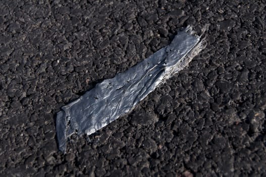 An Old Peice of Duct Tape Stuck to the Asphalt