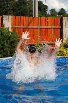 Boy jumping in the home garden swimming pool with clear water