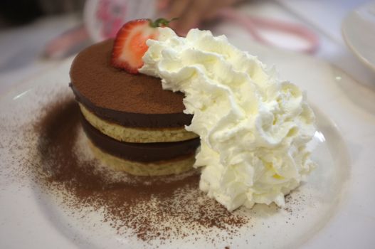 Layered pancakes and chocolate mousse topping with strawberry and whipped cream