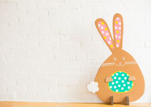 Decoration for Easter. Rabbit of cardboard on a white brick wall