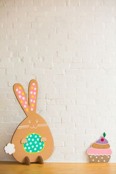 Decoration for Easter. Rabbit of cardboard on a white brick wall