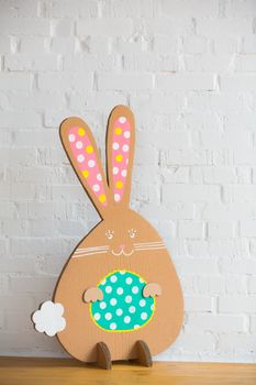 Decoration for Easter. Rabbit of cardboard on a white brick wall