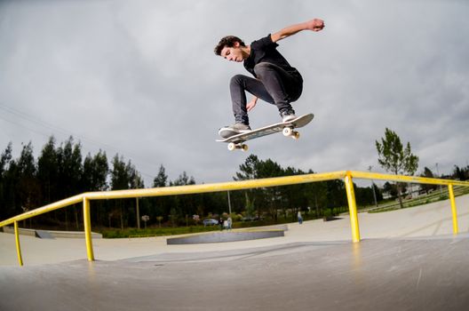 Skateboarder doing a ollie over the rail at the skate park.