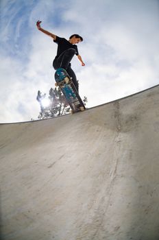 Skateboarder doing a tail slide on a croncrete pool at the skate park.