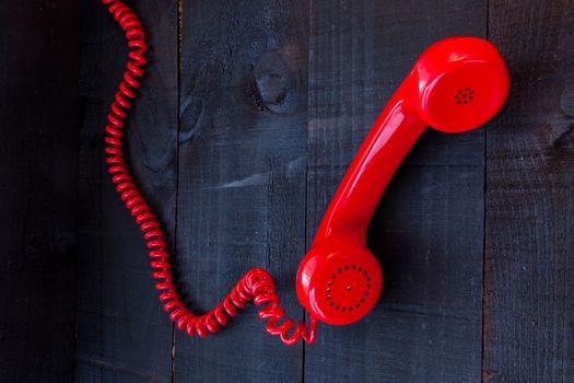 The image represents a vintage red phone on a dark wood background conceptualizing communication or lack thereof