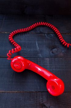 The image represents a vintage red phone on a dark wood background conceptualizing communication or lack thereof