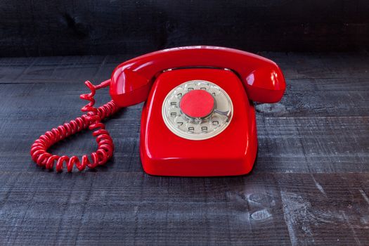 The image represents a vintage red phone on a dark wood background conceptualizing communication or lack thereof