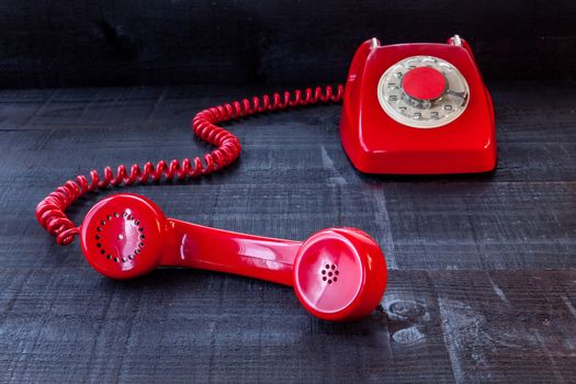 The image represents a vintage red phone on a dark wood background conceptualizing communication or lack thereof