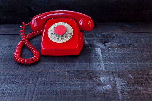 The image represents a vintage red phone on a dark wood background conceptualizing communication or lack thereof