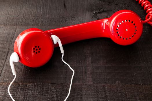 The image represents a vintage red phone on a dark wood background conceptualizing communication or lack thereof