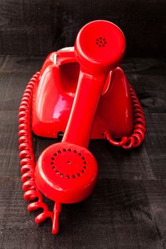 The image represents a vintage red phone on a dark wood background conceptualizing communication or lack thereof