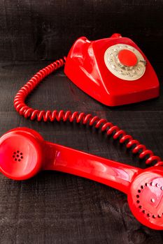 The image represents a vintage red phone on a dark wood background conceptualizing communication or lack thereof