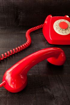 The image represents a vintage red phone on a dark wood background conceptualizing communication or lack thereof