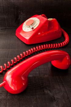 The image represents a vintage red phone on a dark wood background conceptualizing communication or lack thereof