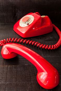 The image represents a vintage red phone on a dark wood background conceptualizing communication or lack thereof