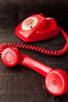 The image represents a vintage red phone on a dark wood background conceptualizing communication or lack thereof