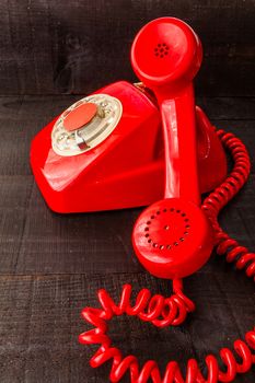 The image represents a vintage red phone on a dark wood background conceptualizing communication or lack thereof