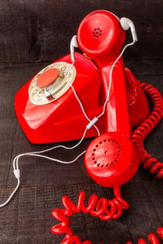 The image represents a vintage red phone on a dark wood background conceptualizing communication or lack thereof