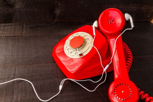 The image represents a vintage red phone on a dark wood background conceptualizing communication or lack thereof