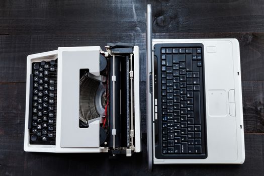 The image represents a retro typewriter and a laptop on a dark wood background conceptualizing that the time of technology is getting older the picture is taken from a top view