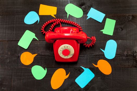 A retro red telephone surrounded by speech balloons which conceptualizing a moment of stress or excessive communication