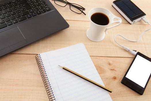 Collection of objects of an freelance worker or someone who works at home, on wooden background illuminated with natural light and photographed from above