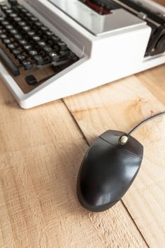 The image shows an antique typewriter connected to a computer mouse imitating a laptop and conceptualizing the obsolescence of technology