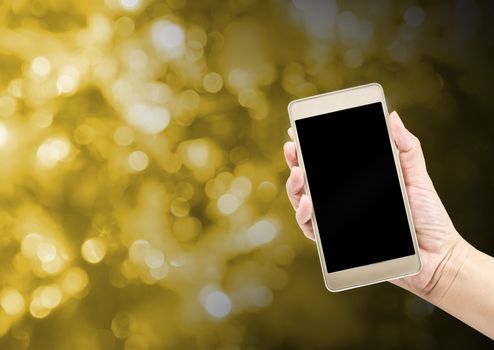 Mobile phone in hand on gold color blur background