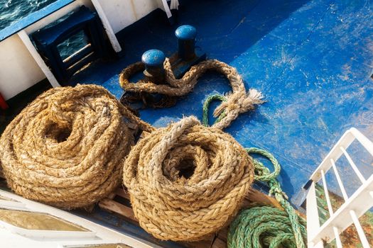 Two old fleecy ropes curtailed into a spiral on the deck of the vessel