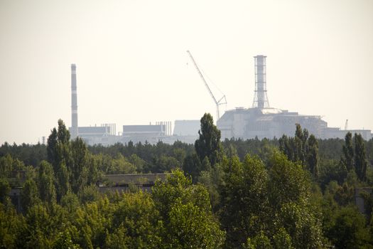 Forest and Chernobyl nuclear reactor in the background, it was covered with sarcophagus and abandoned after nuclear disaster in Chernobyl at 26.04.1986 (taken from Pripyat)