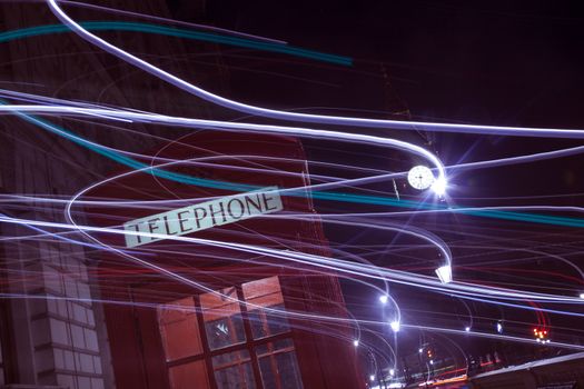 London telephone box and Big Ben in background at night. With light trails.