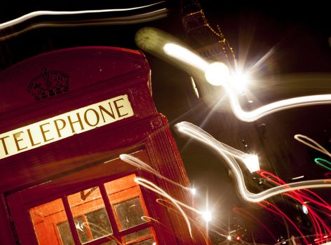 London telephone box and Big Ben in background at night. With light trails.