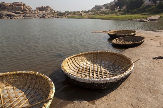 Round stereotypic boats and hills with amazing stones at Hampi temple complex in India