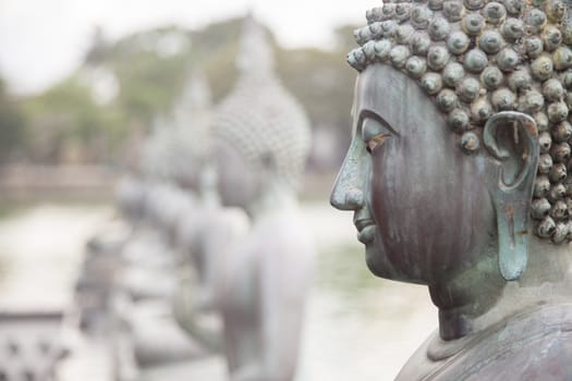 Statute of Buddha in a row. Close-up on the face of Buddha.