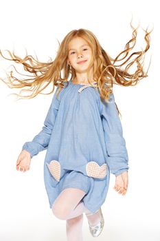 Jumping little girl in a blue dress with flying curls