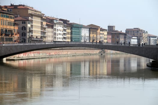 People walking over a bridge across Arno river in Pisa, Italy