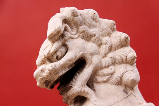 Lion on red background taken infront of an entrance on a garden of the Forbidden City in Beijing, China